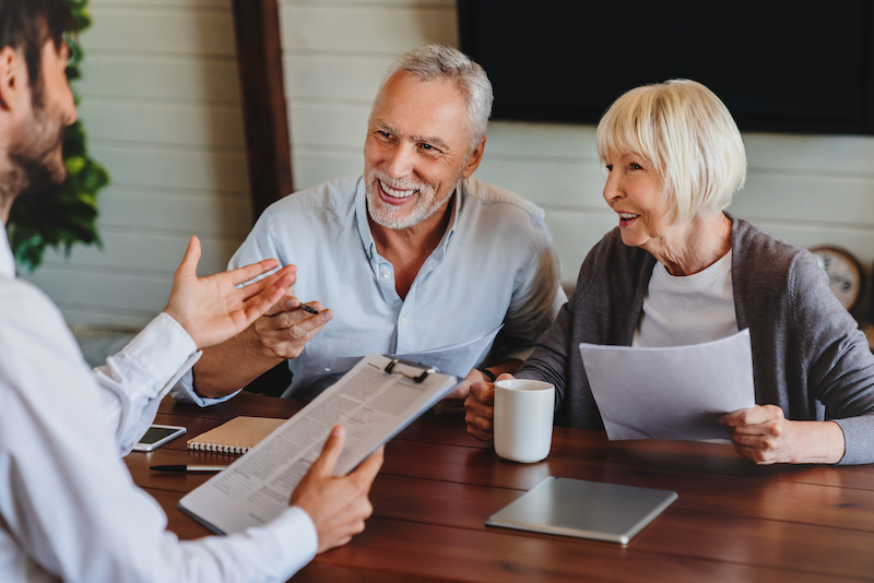 Happy aged couple consulting with investment buyers agent at home